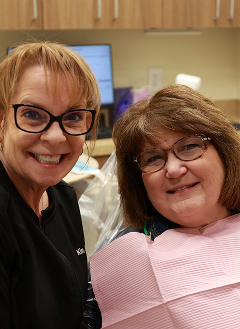 Dental team member and patient with glasses smiling